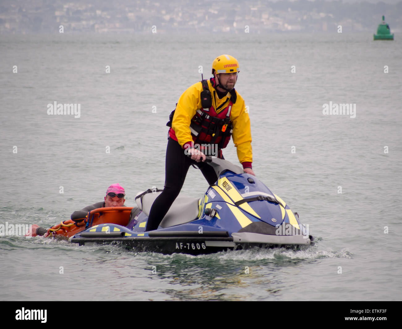 Un socorrista de una moto de agua ayuda a un nadador que está en dificultad, durante un evento en el Solent triatlón Foto de stock