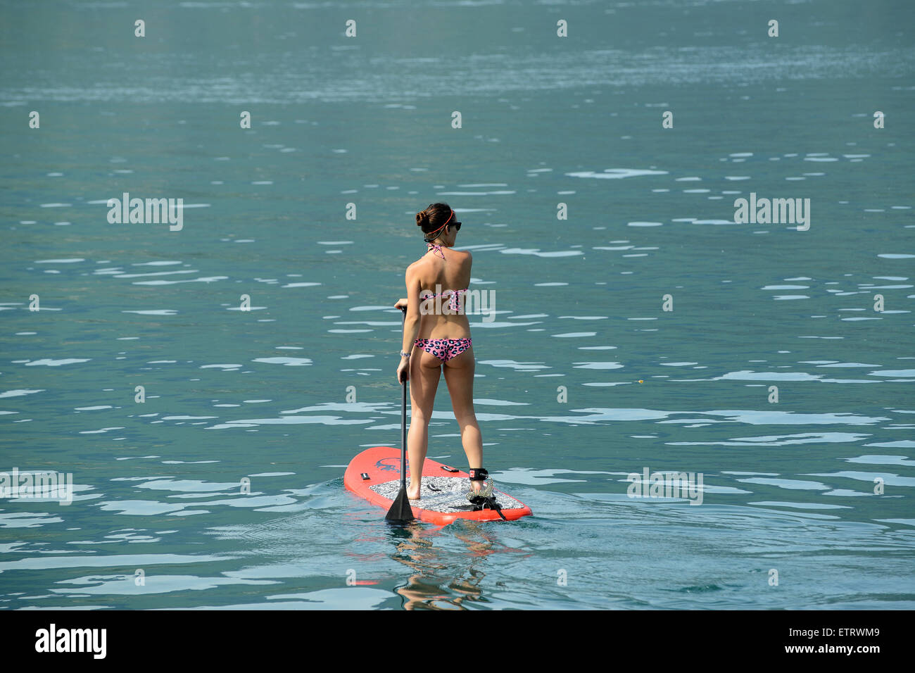 Mujer en bikini el Stand Up Paddle Surf o paleta permanente el embarque en el lago de Annecy en Francia Foto de stock
