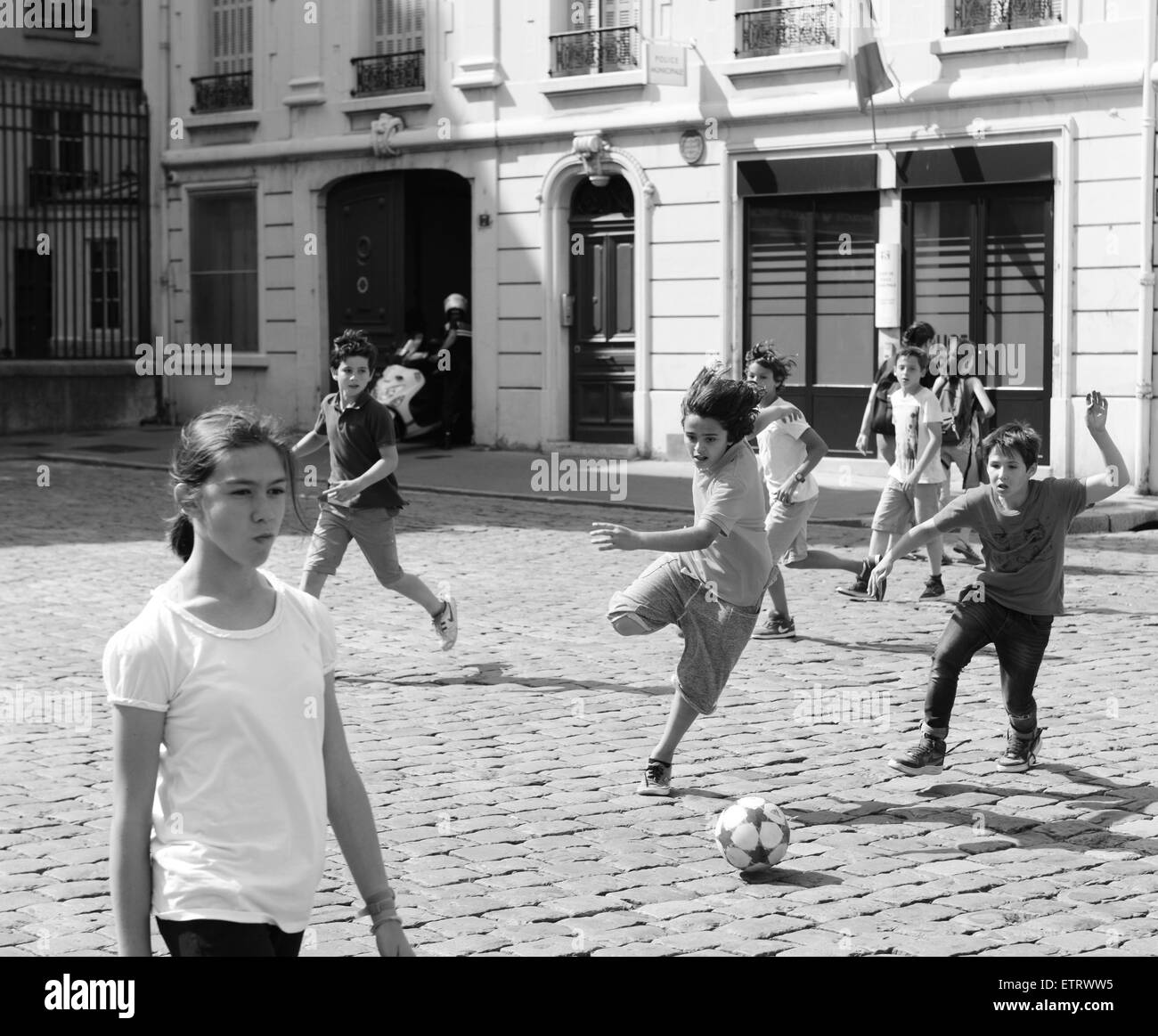 Los niños chicos jugando al fútbol en la calle adoquinada en Lyon Francia Europa Foto de stock