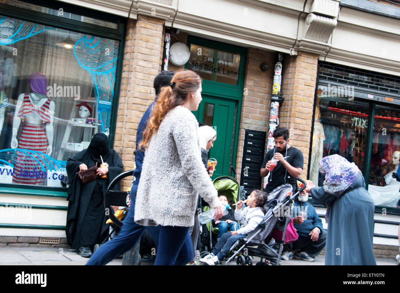 Brick Lane Londres 2015.En la calle, familia de Bangladesh y transeúntes por delante de la tienda de ropa Rokit Foto de stock