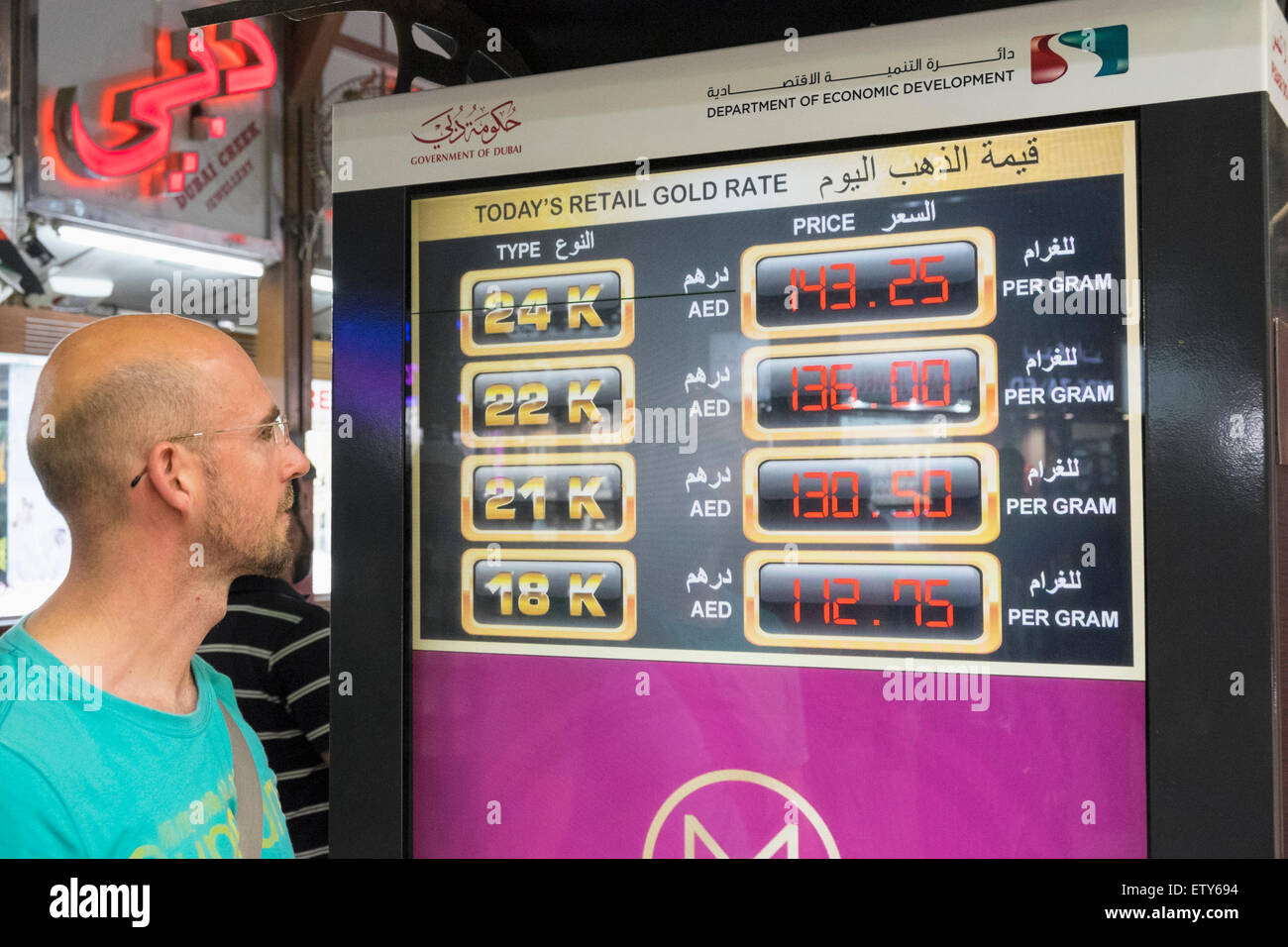 Turista mirando el precio actual del oro en pantalla electrónica en el zoco del oro en Deira, Dubai, Emiratos Árabes Unidos Foto de stock