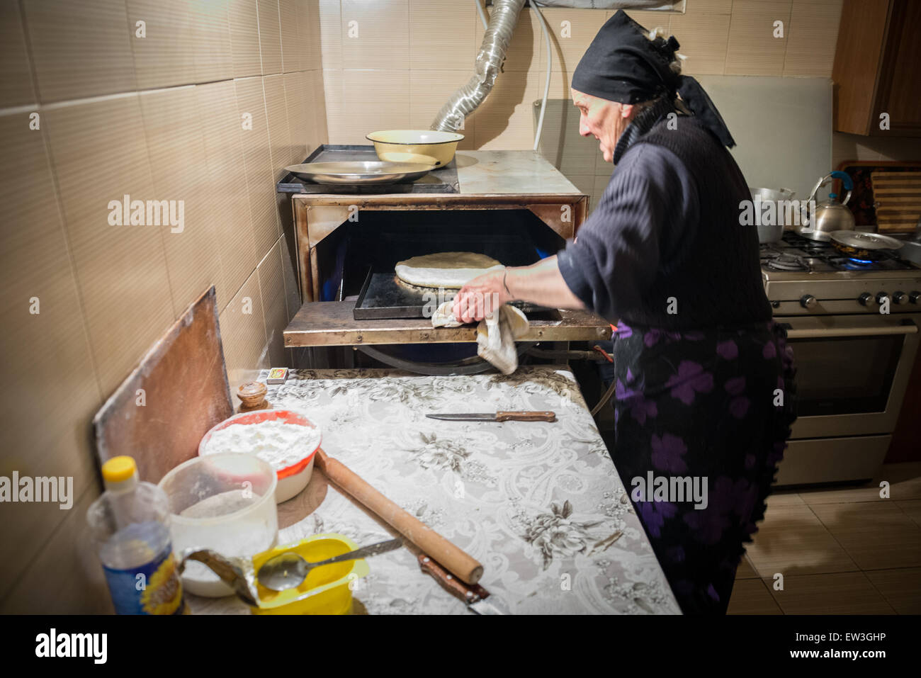 Mujer georgiana haciendo pan en el pequeño bar de la ciudad (antiguamente Stepantsminda Kazbegi) situado en las montañas del Cáucaso, Georgia Foto de stock