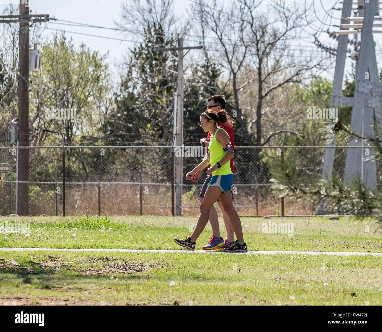 Una joven pareja caucásica en ejercicio de ropa, la mujer con un contador de pasos en su brazo, recorrer los senderos en el lago Hefner, Oklahoma City, Oklahoma, Estados Unidos. Foto de stock