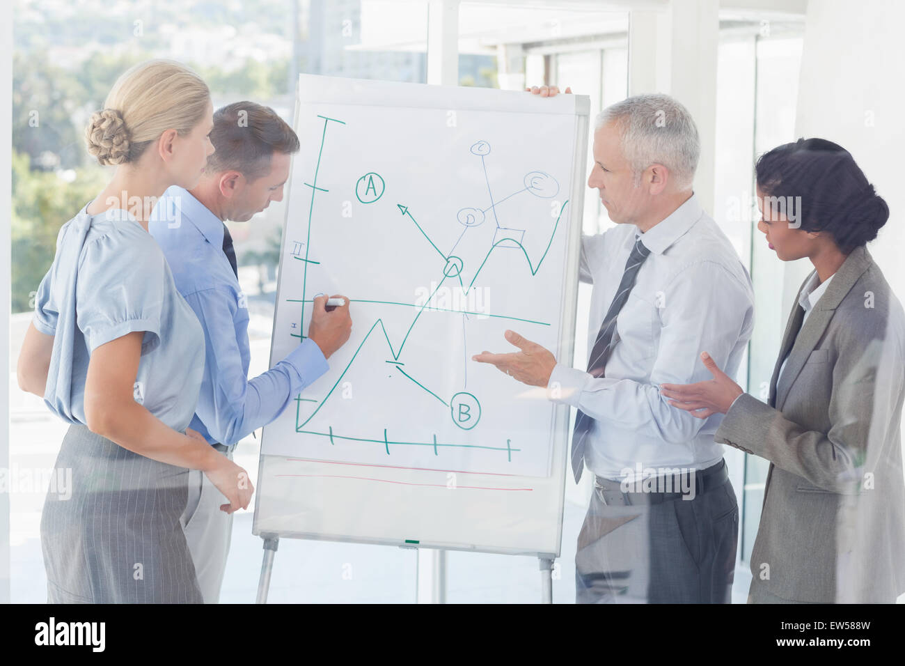 Equipo empresarial hablando de el gráfico en la pizarra Foto de stock