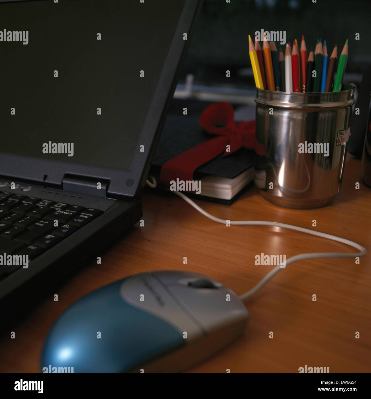 Close-up de ordenador portátil con el mouse sobre el escritorio con lápices de colores en plata pot Foto de stock