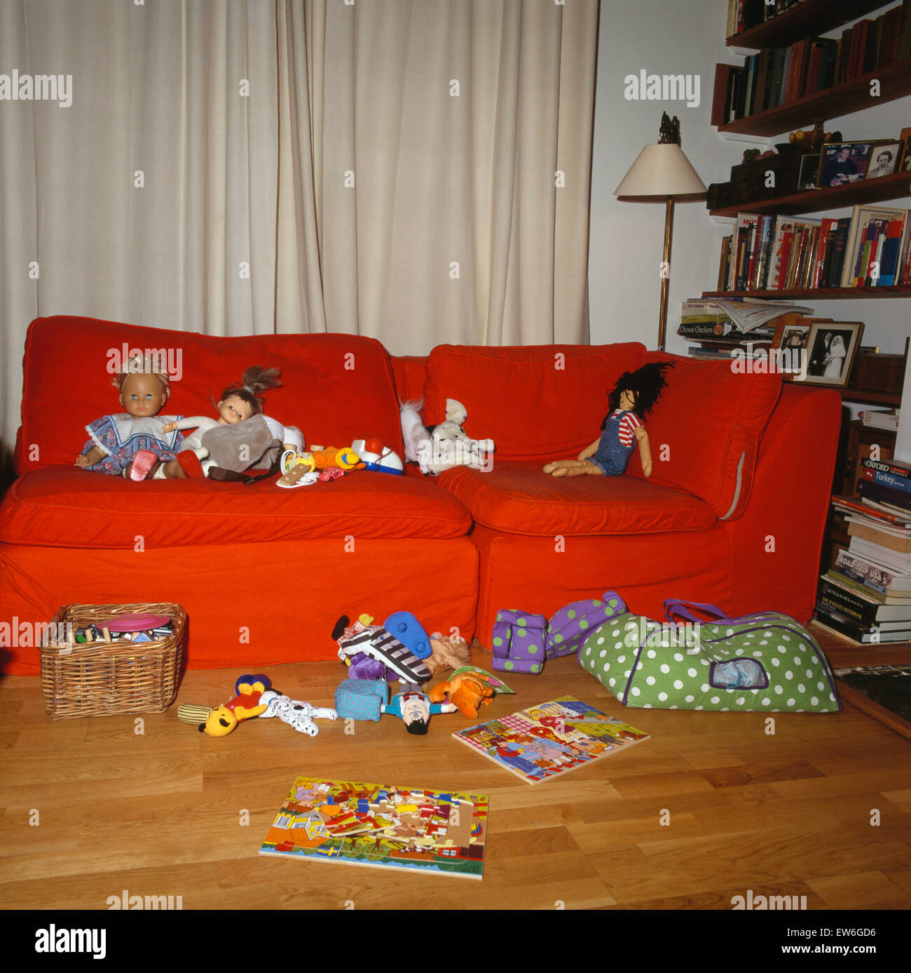 Juguetes en sofá naranja y piso en children's play room desordenados. Foto de stock