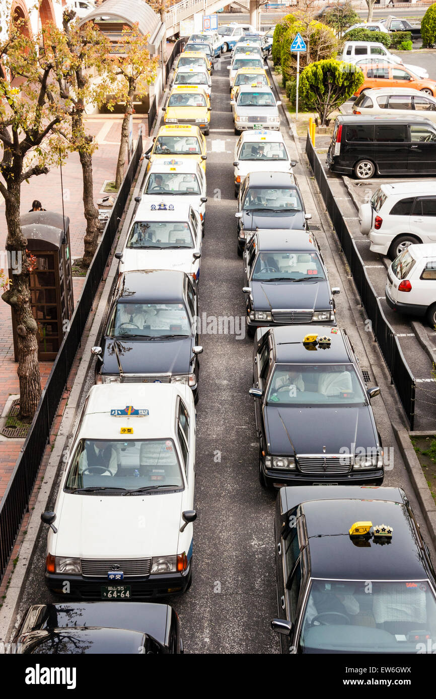 Vista aérea de la doble fila de taxis esperando en la carretera, taxis  amarillos, negros y blancos fuera de la estación (no se muestran), en  Kurashiki en Japón Fotografía de stock -
