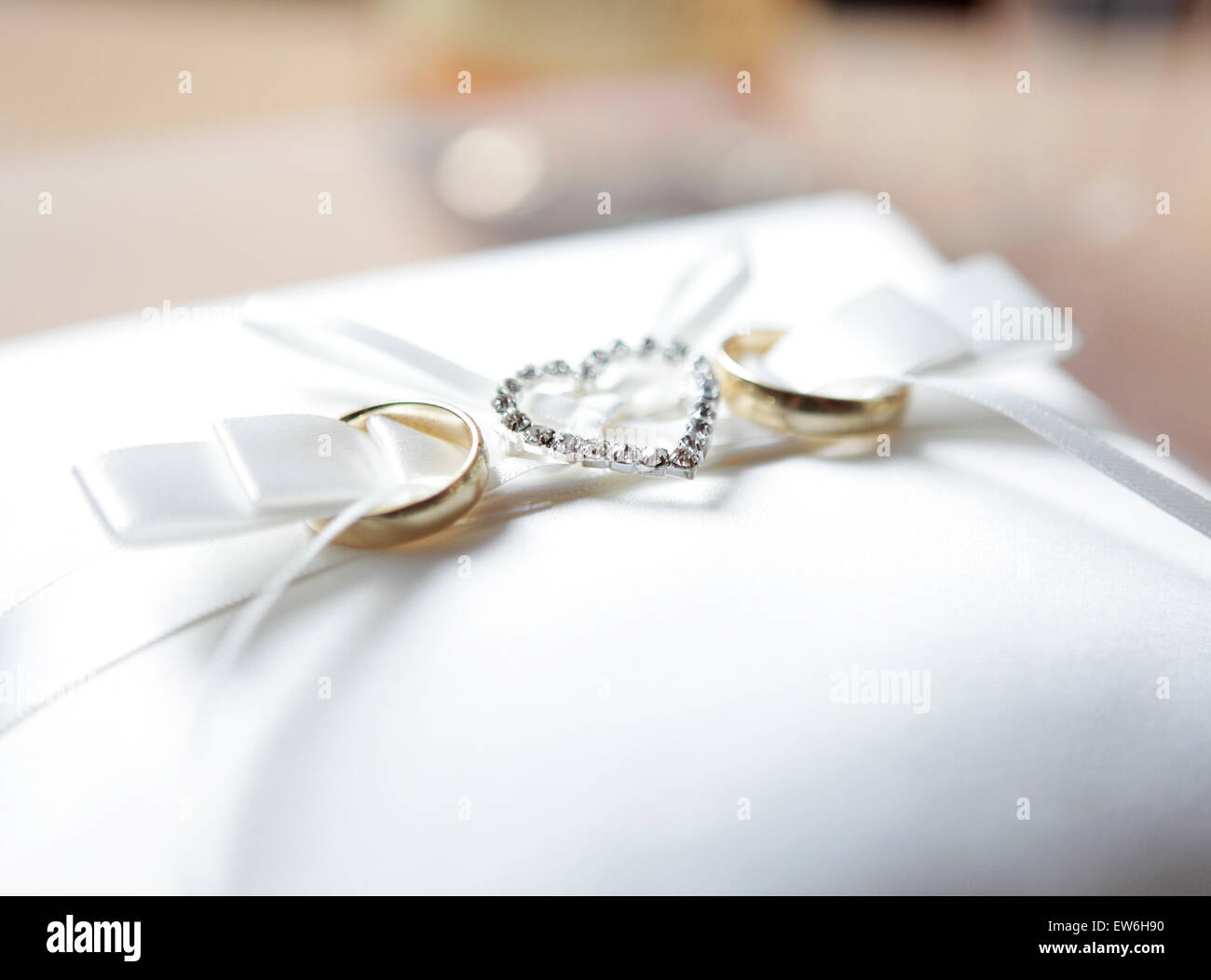 Sobre un cojín de terciopelo blanco son dos anillos decorados con un corazón de diamantes Foto de stock