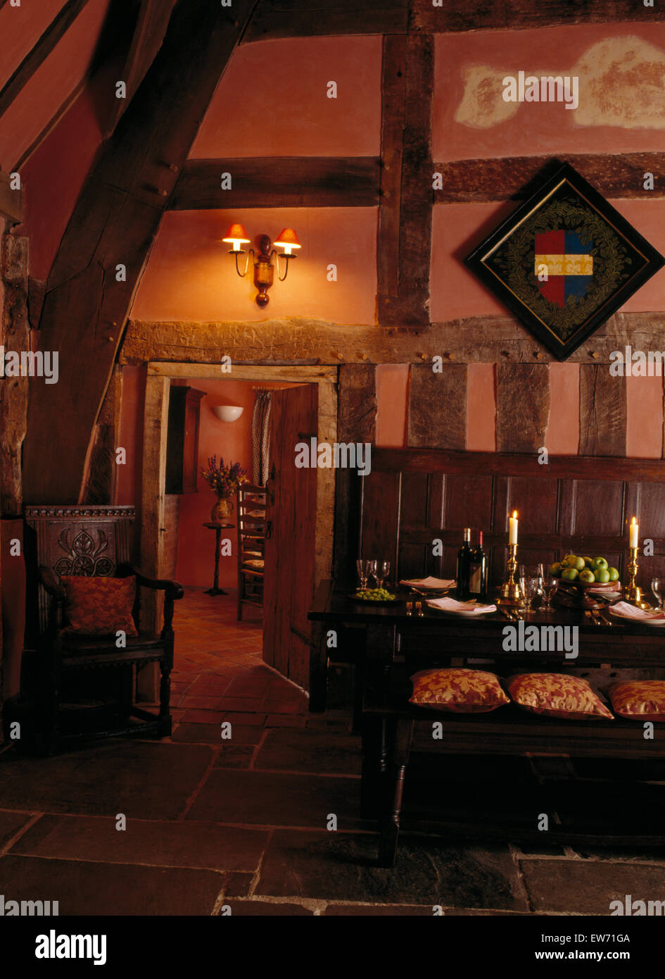 Juego de mesa para cenar en el comedor de estilo Tudor con vigas iluminado con luces de pared y un roble resolver Foto de stock