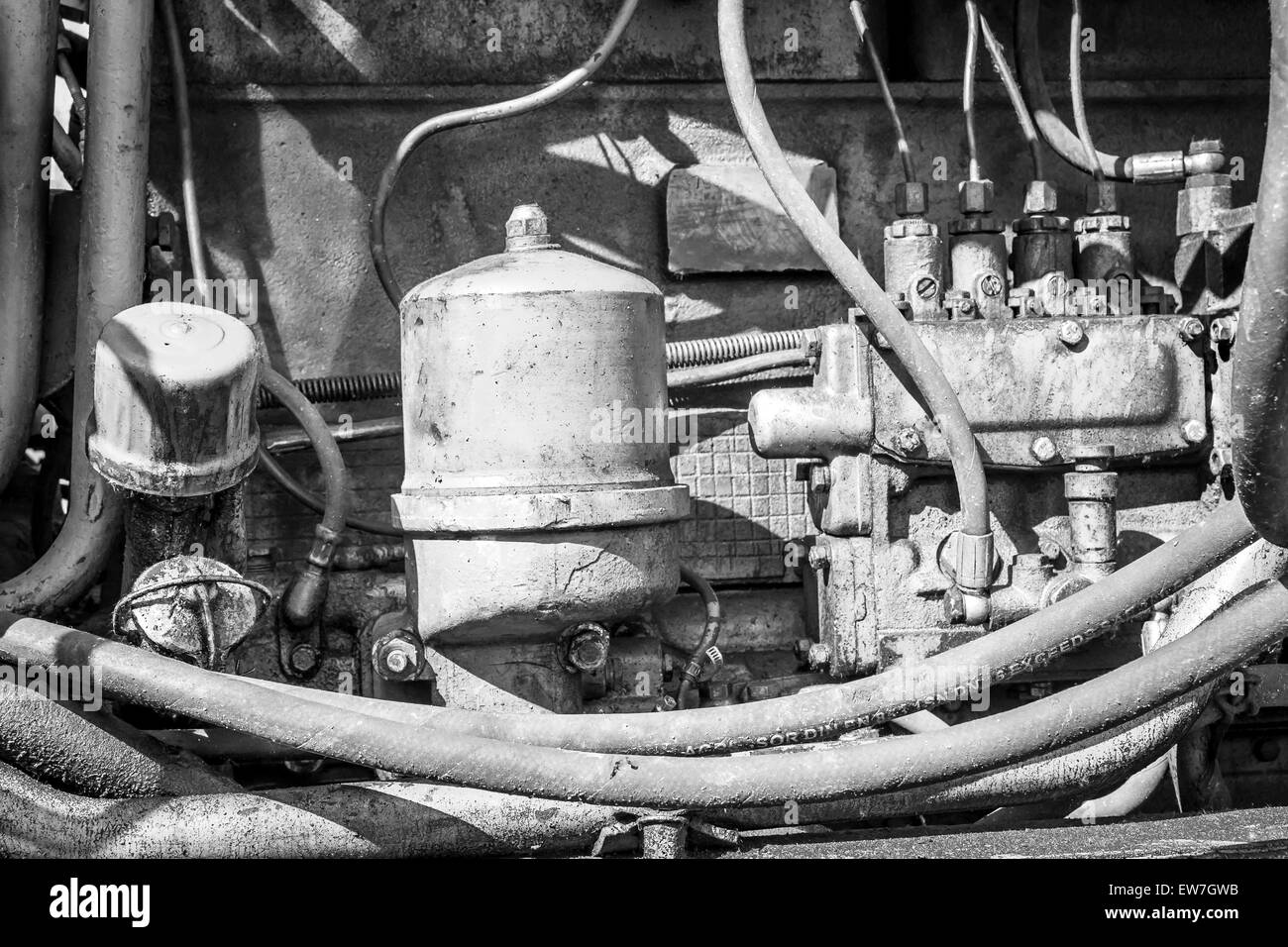 Close-up de un manchado de aceite del compartimento del motor de una máquina excavadora industrial Amarillo tierra en monocromo Foto de stock