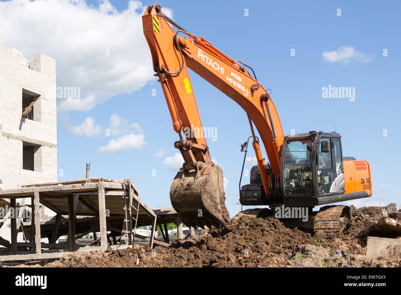 Orange digger excava el suelo en preparación de nuevos apartamentos para familias jóvenes en la ciudad de Ufa Bashkortostan Rusia en junio de 2015 Foto de stock