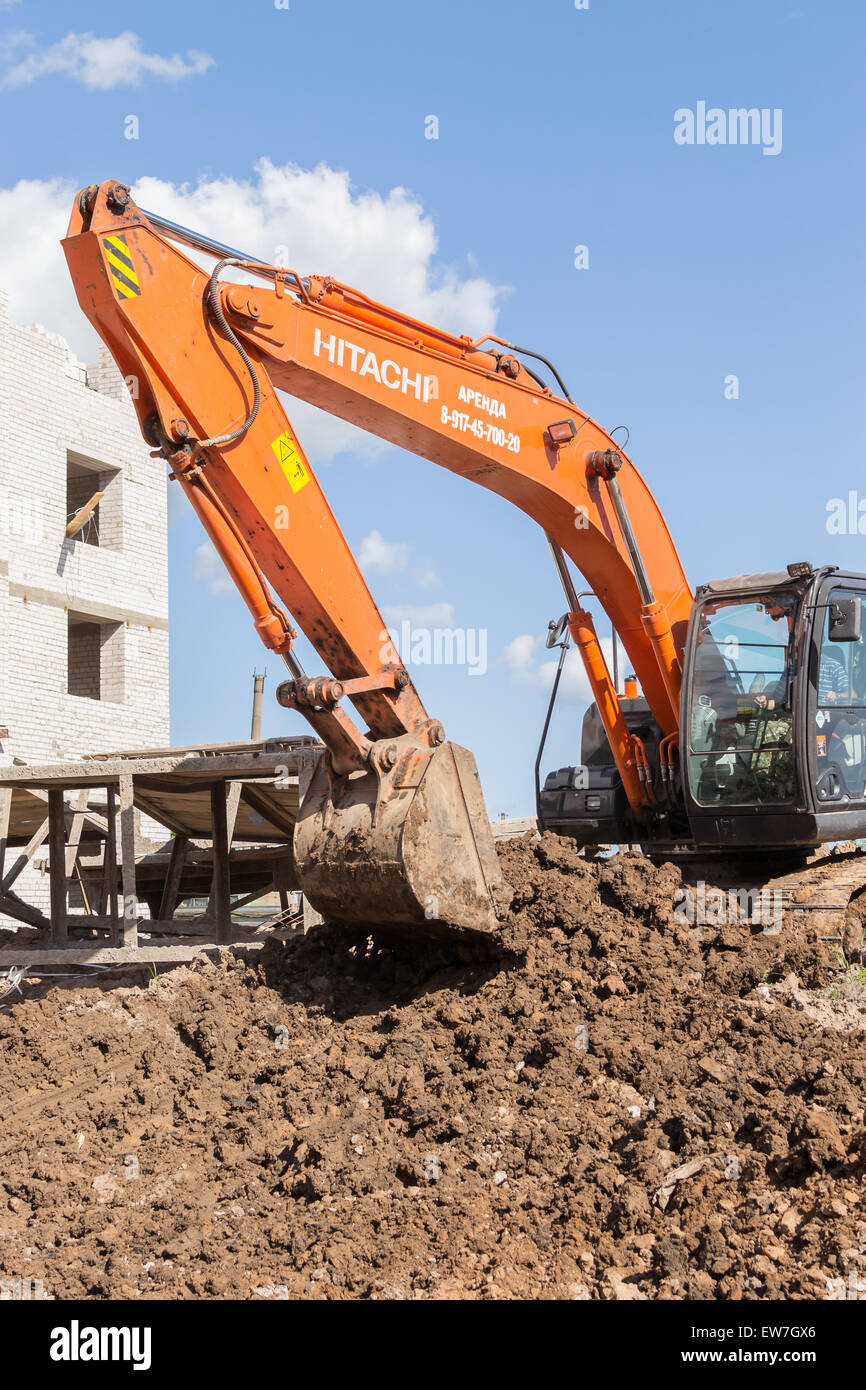 Orange digger excava el suelo en preparación de nuevos apartamentos para familias jóvenes en la ciudad de Ufa Bashkortostan Rusia en junio de 2015 Foto de stock