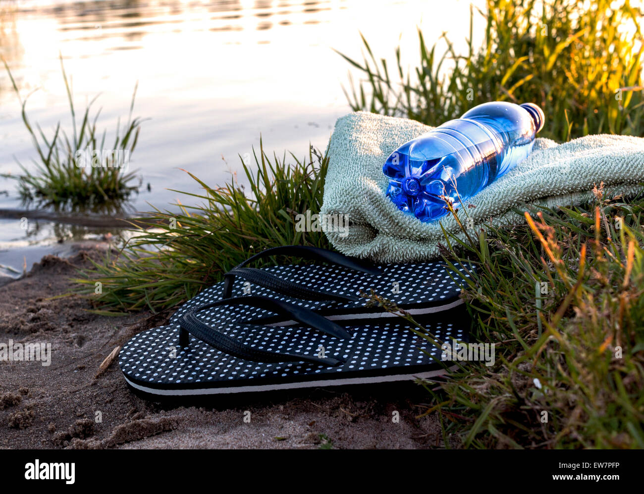 Nadar en el río solitario bronceado chanclas toalla, botella de agua río closeup primavera verano Fotografía de stock - Alamy