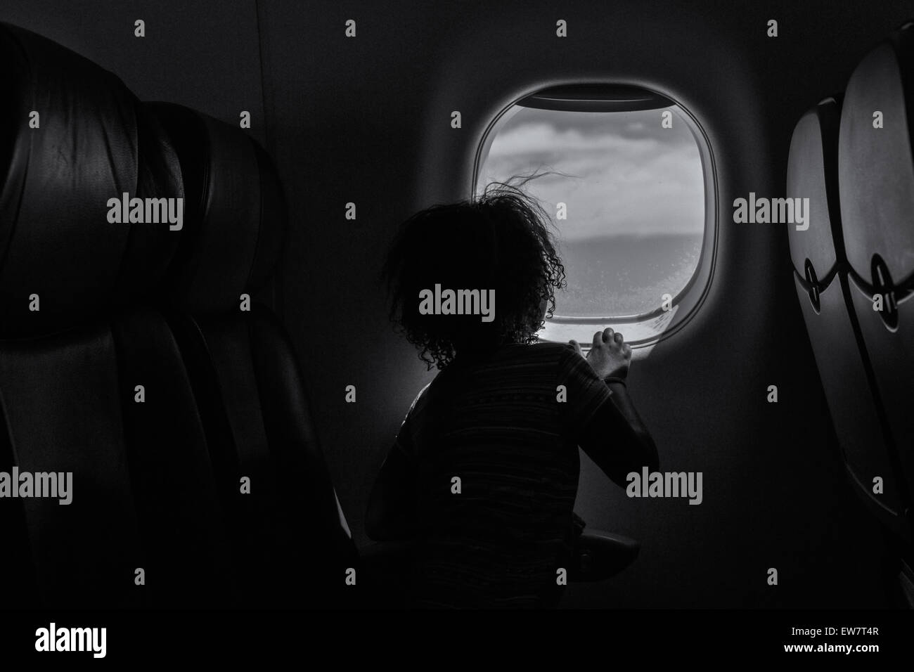 Vista trasera de una chica mirando por la ventana en un avión Foto de stock