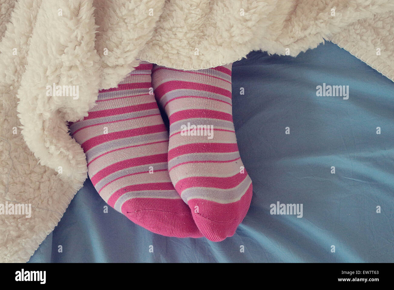 Pies de mujer en rosa calcetines que sobresalen por debajo de una manta  Fotografía de stock - Alamy