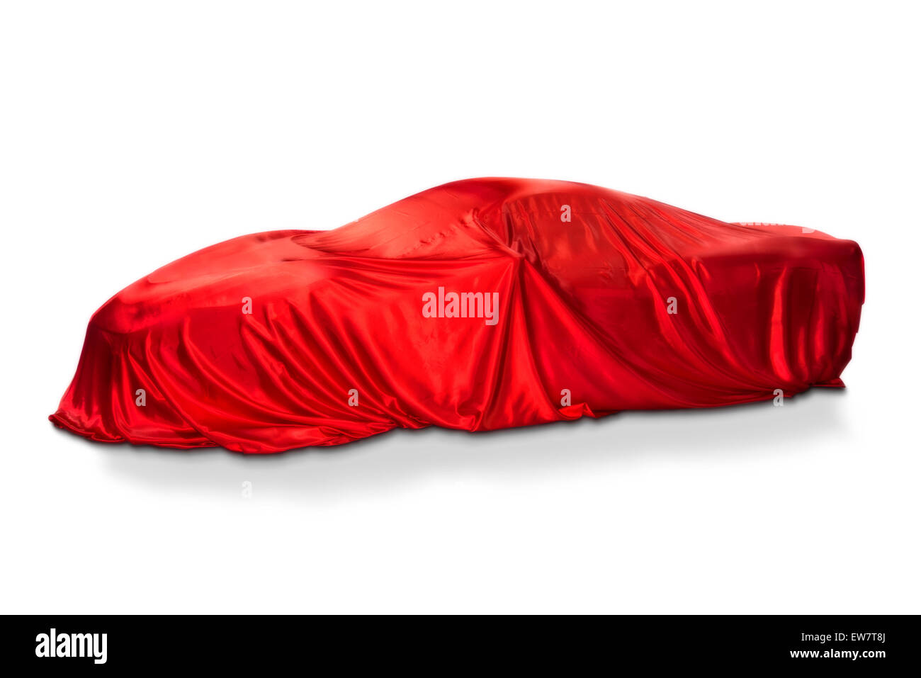 Un coche deportivo está cubierto con un trapo rojo. Foto de stock
