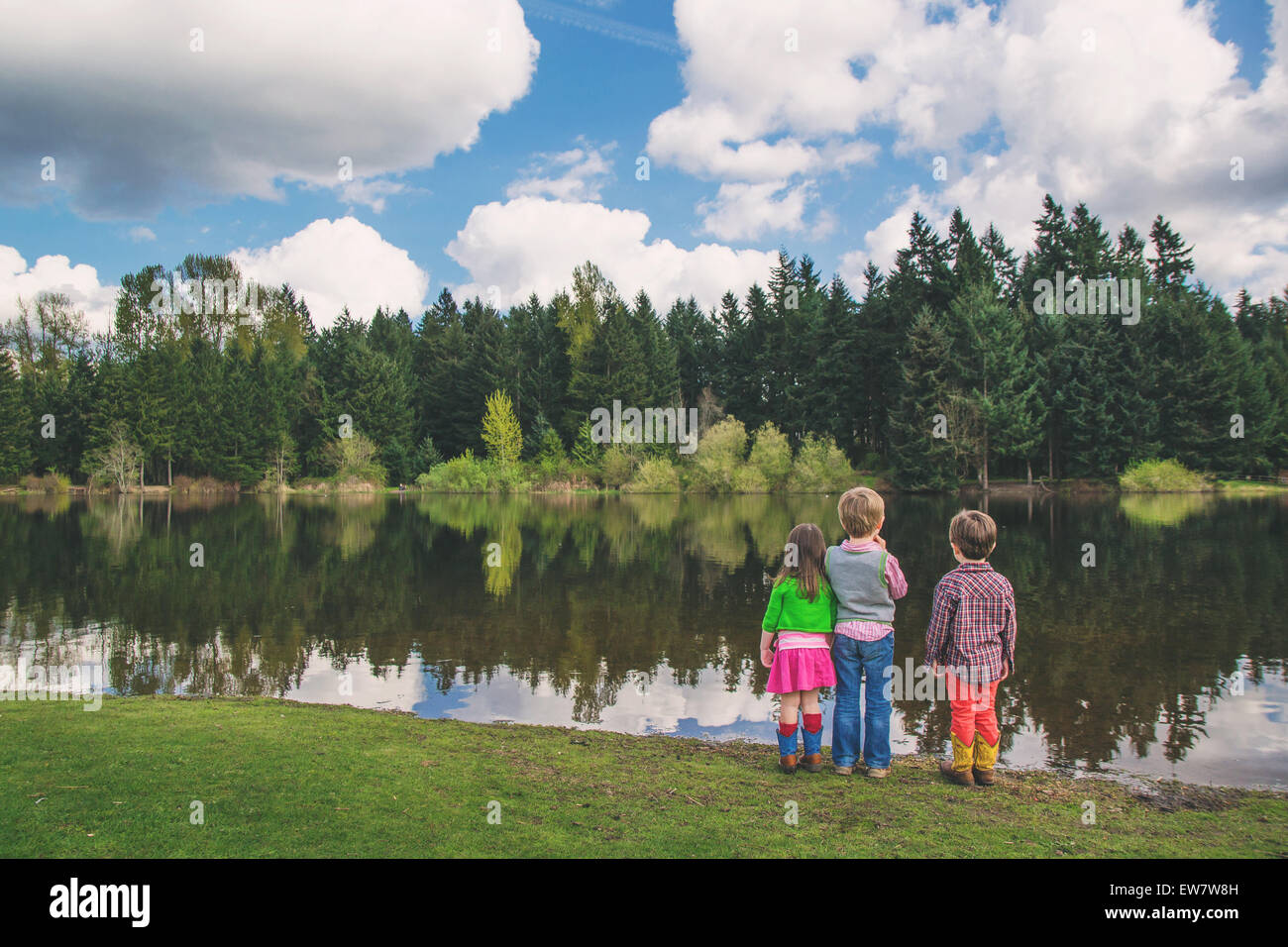 Tres niños mirando el lago Foto de stock