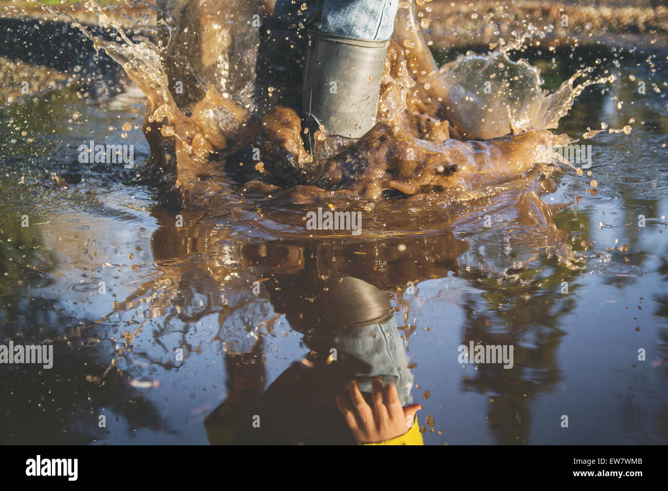 Primer plano de las piernas del niño salpicando en un charco de agua, EE.UU Foto de stock