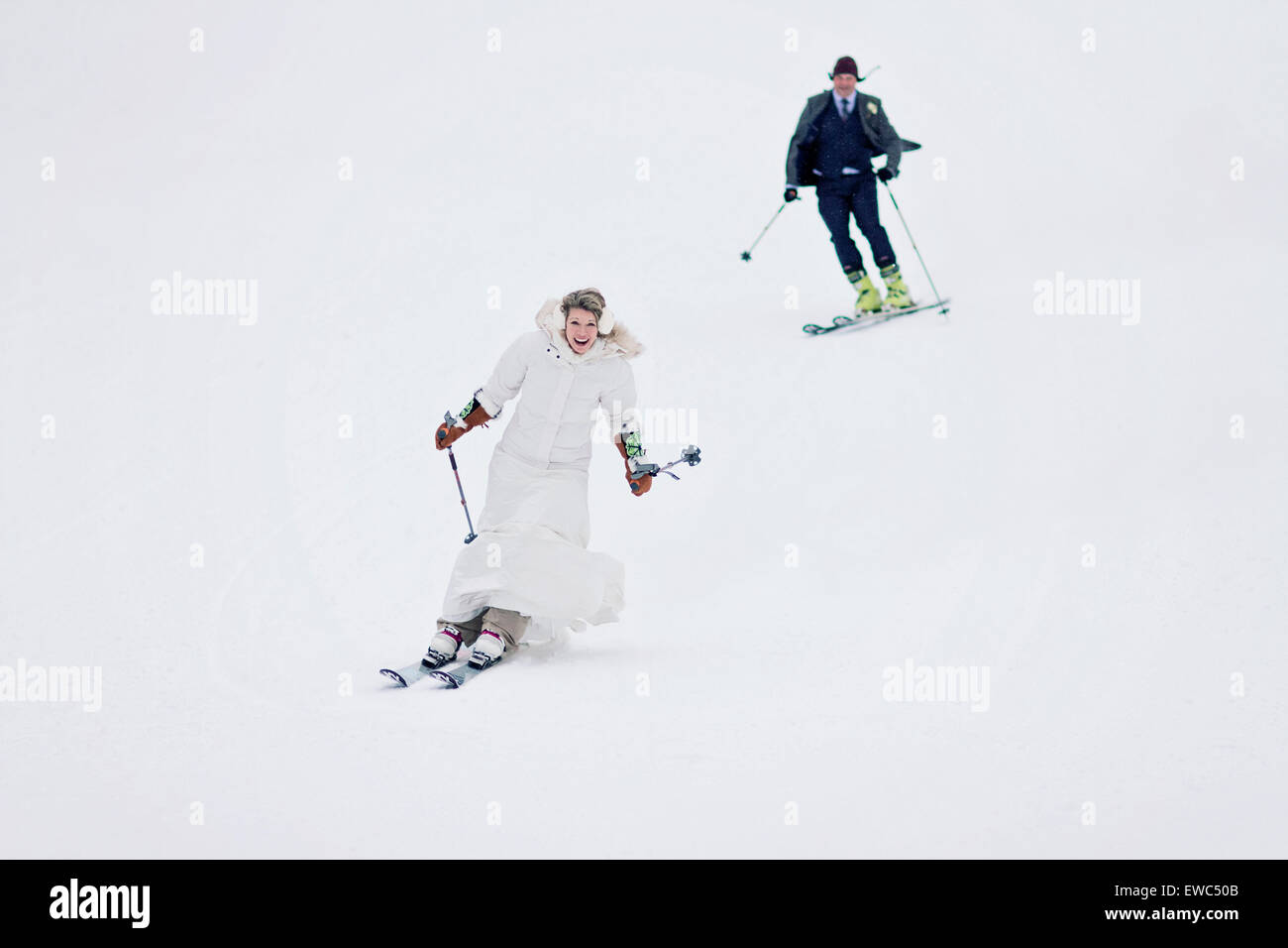 Una pareja de recién casados juntos esquí montaña abajo después de casarse. Foto de stock