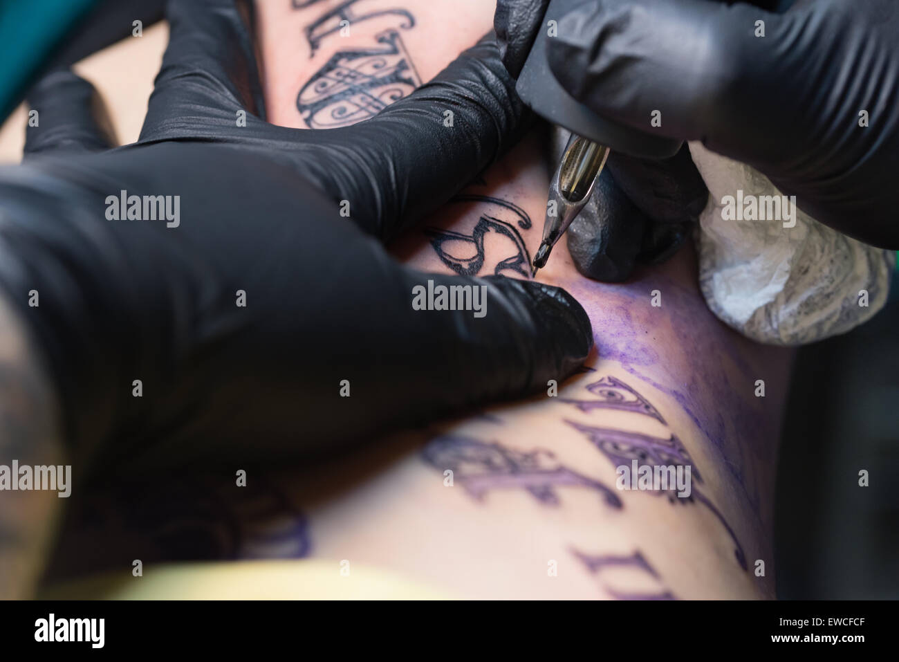 Una mujer obteniendo un script negro tatuaje en la caja torácica. Foto de stock