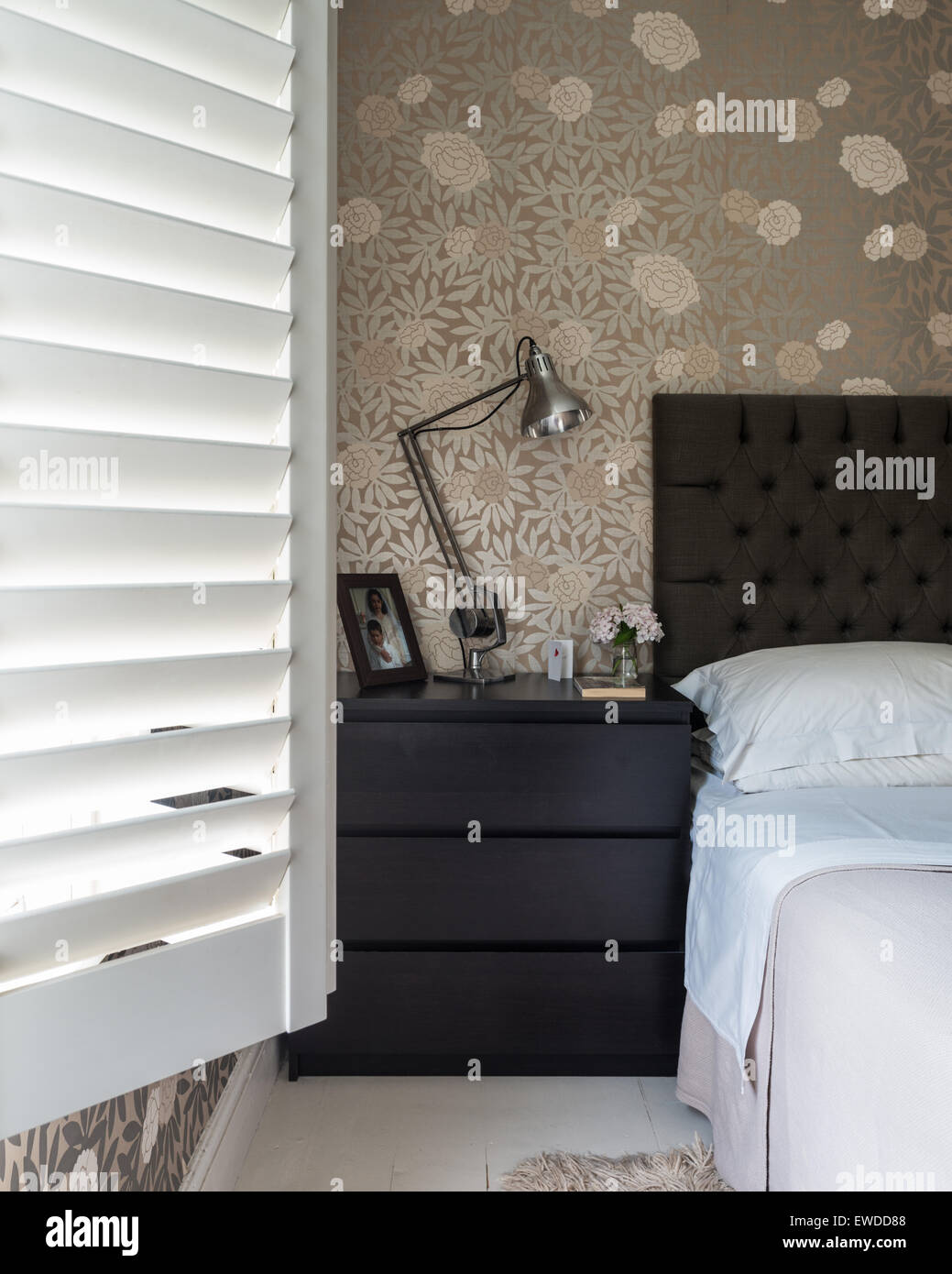 Osbourne & poco metálico imprimir papel tapiz floral en dormitorio con persianas de madera y cabecera seguro Foto de stock