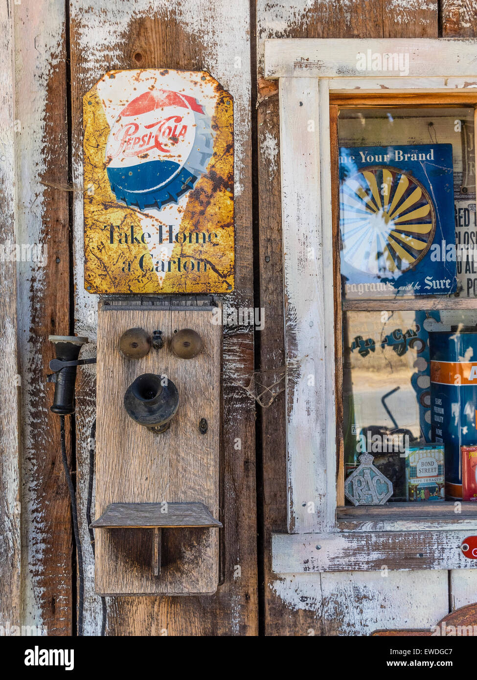 Antiguo teléfono de pared y Pepsi firmar sobre la madera desgastada de una antigua estación de gas. Foto de stock