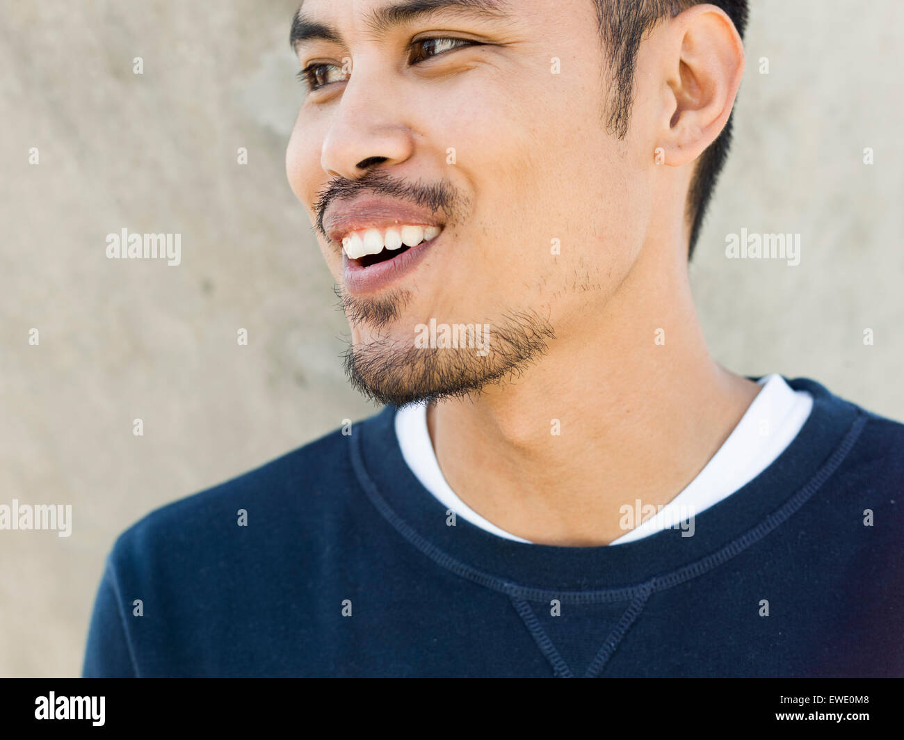 Retrato de una sonriente joven de raza mixta asiática barba mirando lateralmente Foto de stock