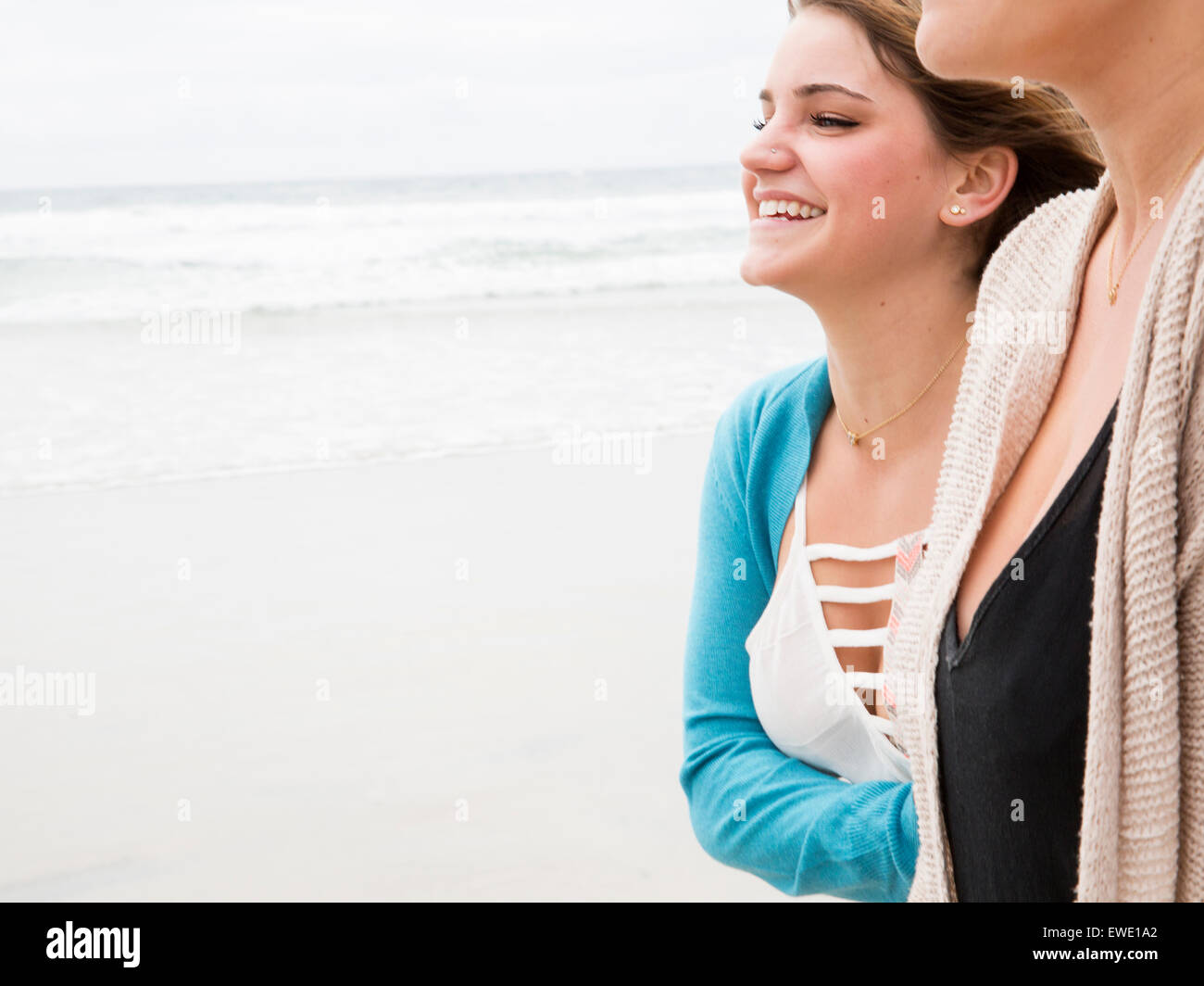 Cerca de dos mujeres jóvenes sonrientes caminando sobre una playa Foto de stock
