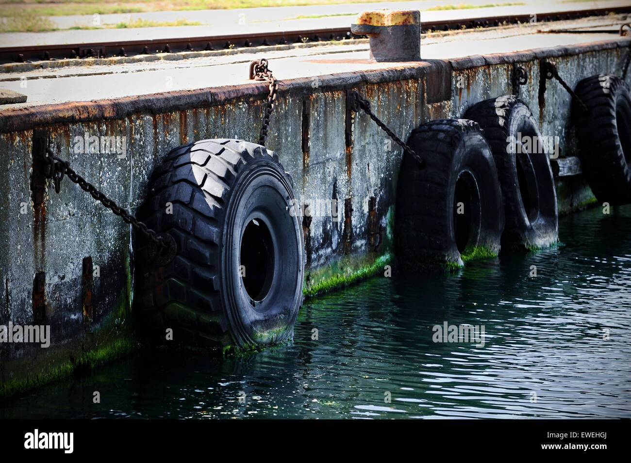 Los grandes neumáticos de camiones usados para tope de baches en un muelle comercial Foto de stock