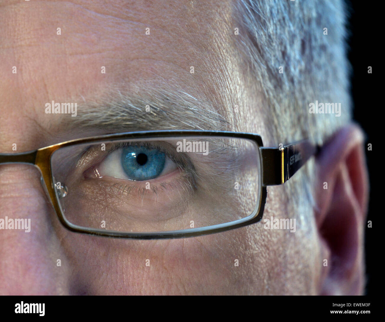 Mitad cara hombre maduro de negocios de cerca con gafas con ojo azul izquierdo Foto de stock