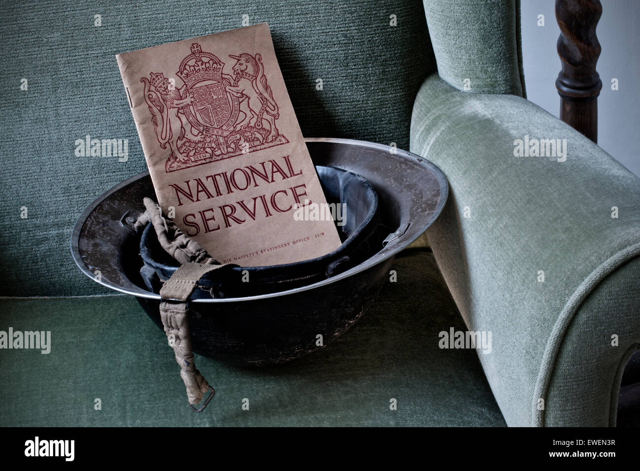 WW2 casco militar en el período silla con 1939 Servicio Nacional "llamada a las armas", folleto de voluntariado suscríbase a deberes de guerra Foto de stock