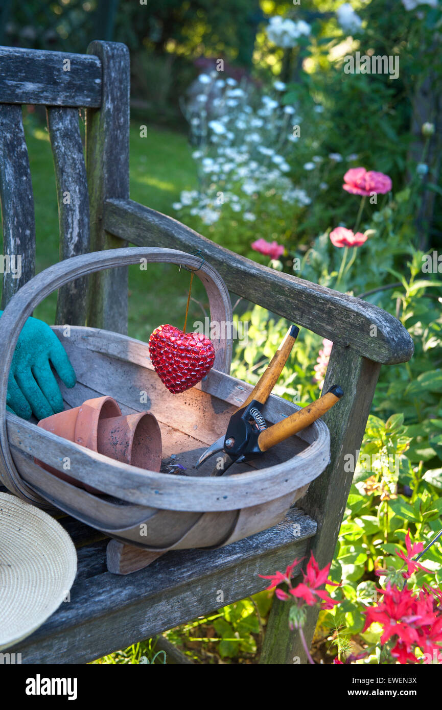 Igualmente Preferencia Ejercicio Silla de jardín rústico en el soleado jardín con accesorios de jardinería y  las TRUG tradicional emblema de corazón decoración 'amor' de jardinería  Fotografía de stock - Alamy