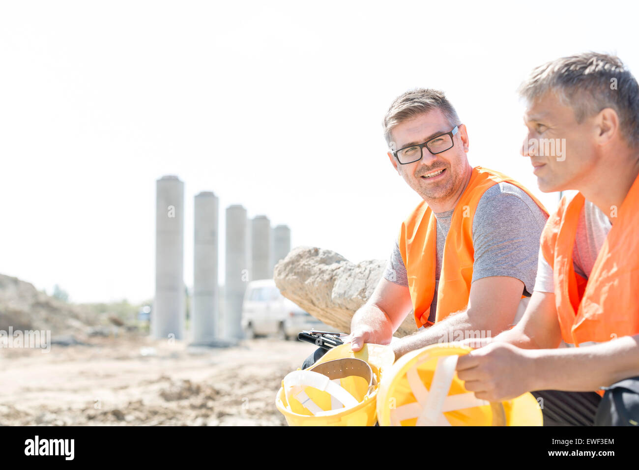 Supervisor sonriente sentado con su colega en el sitio de construcción Foto de stock