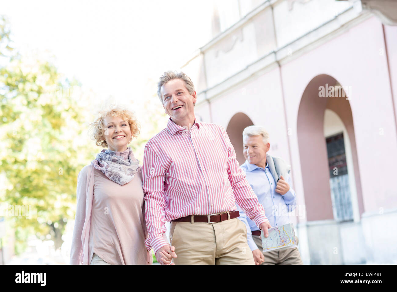 Feliz pareja de mediana edad con mapa caminando en la ciudad Foto de stock