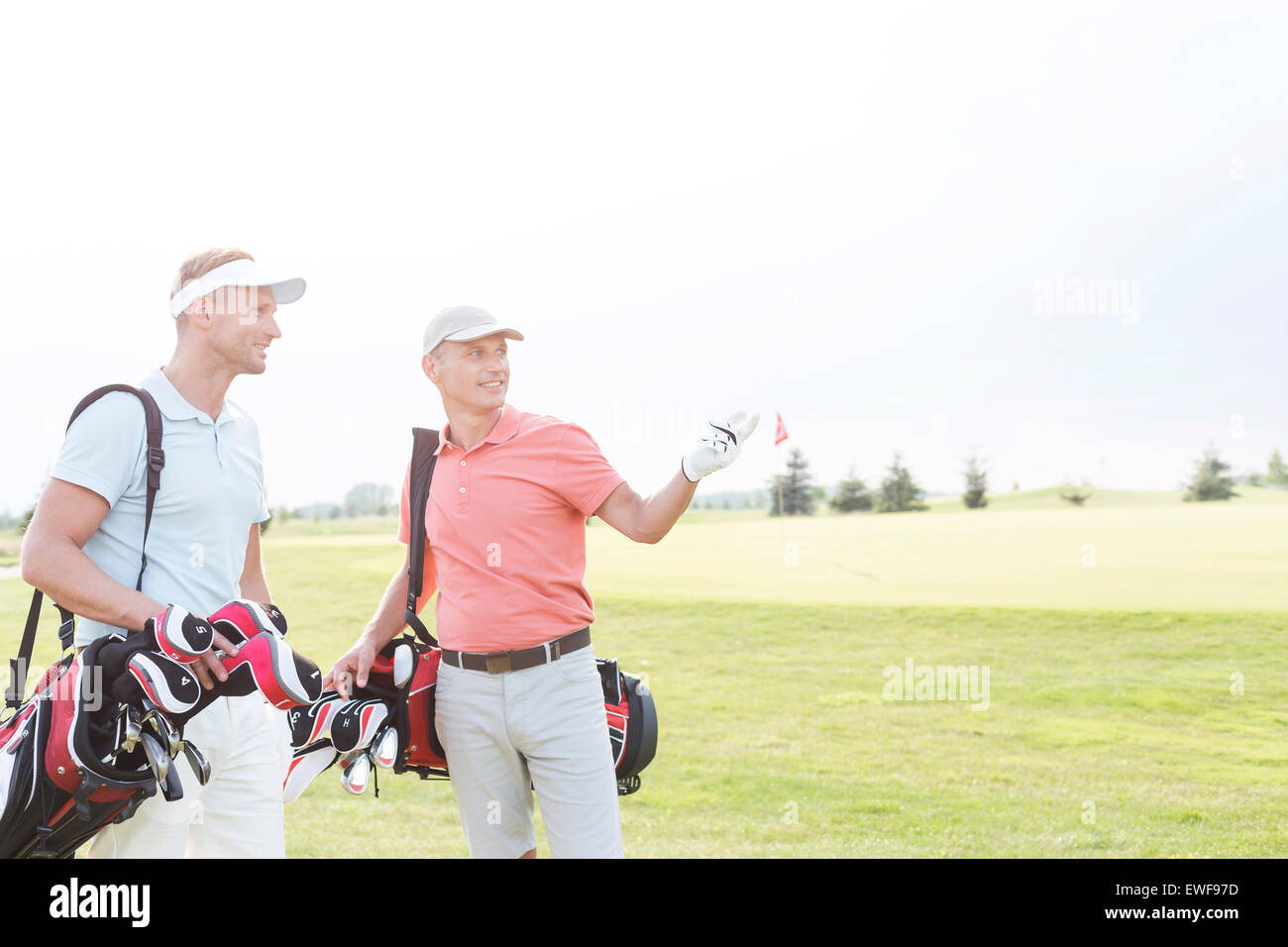 Hombre mostrando algo a un amigo en el campo de golf contra el cielo claro Foto de stock