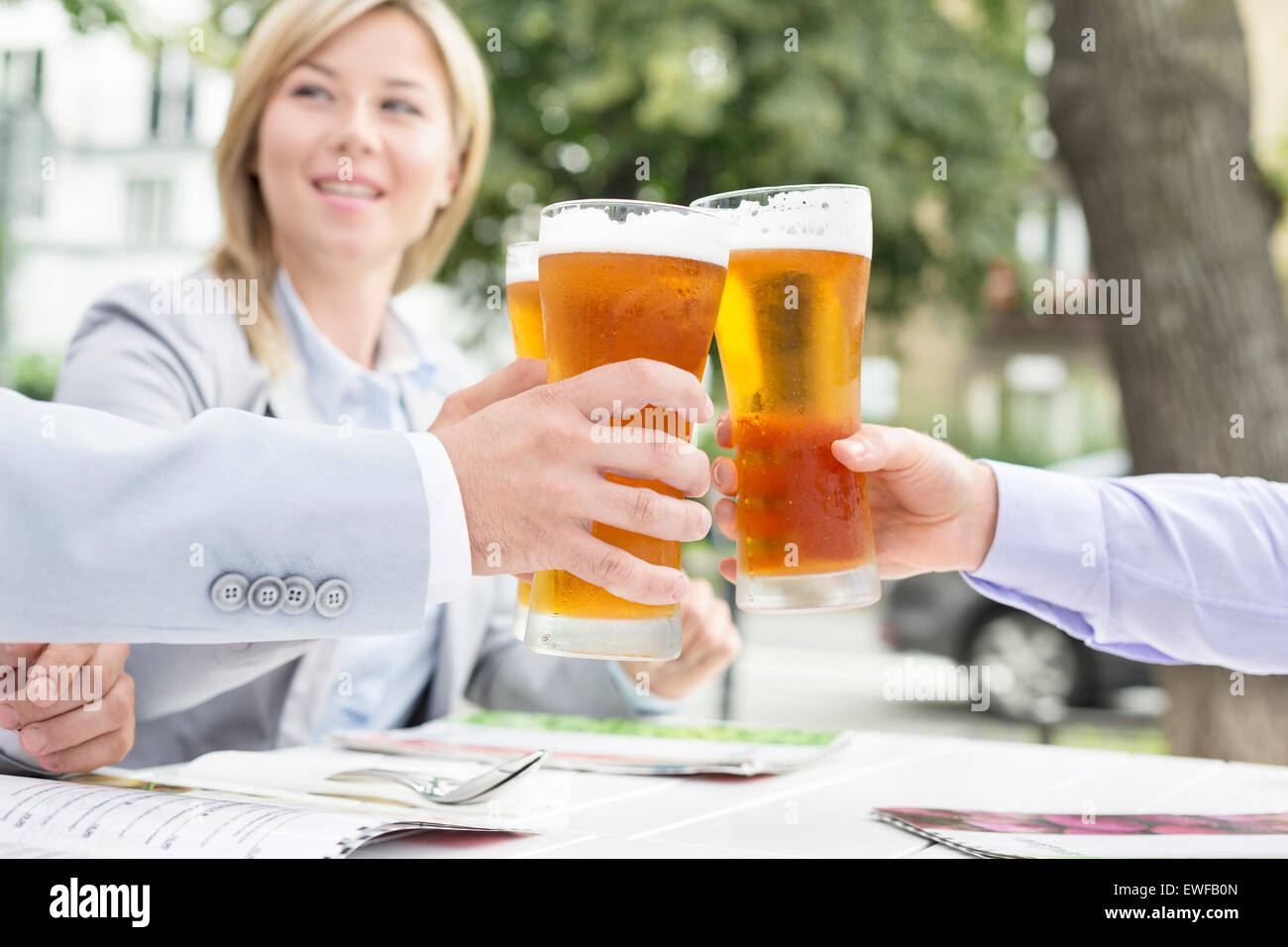 Empresarios de tostar los vasos de cerveza en el restaurante al aire libre Foto de stock