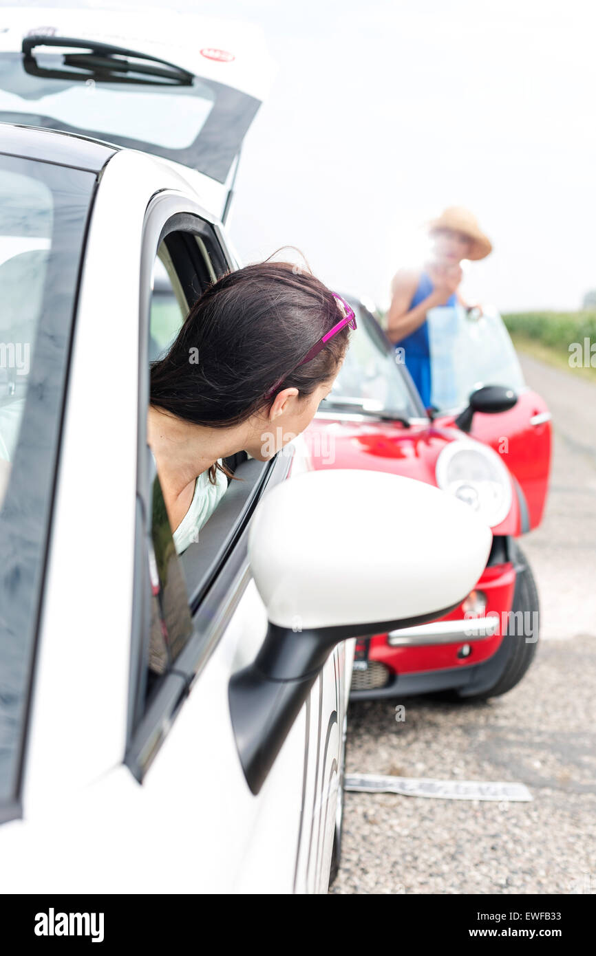 Mujer mirando su coche en carretera estrellándose femenino Foto de stock