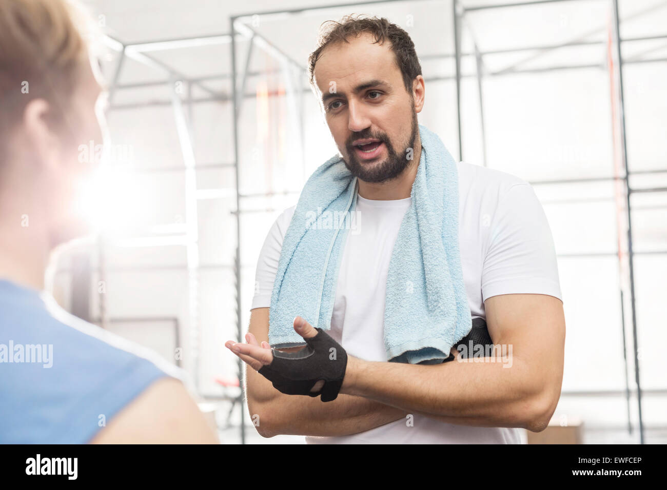 Hombre hablando a amigo masculino en el gimnasio crossfit Foto de stock