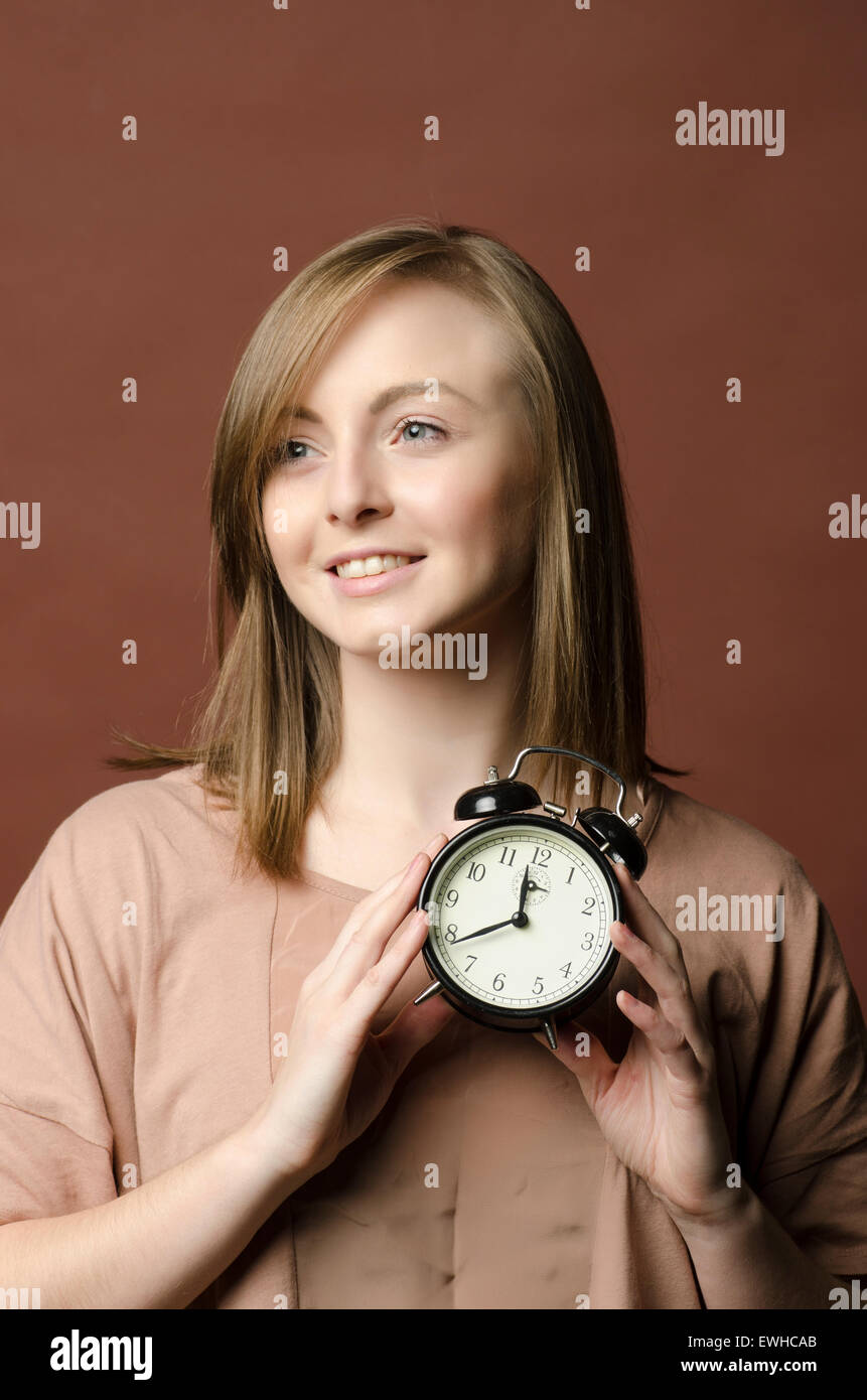Puntual joven sosteniendo un reloj de alarma Foto de stock