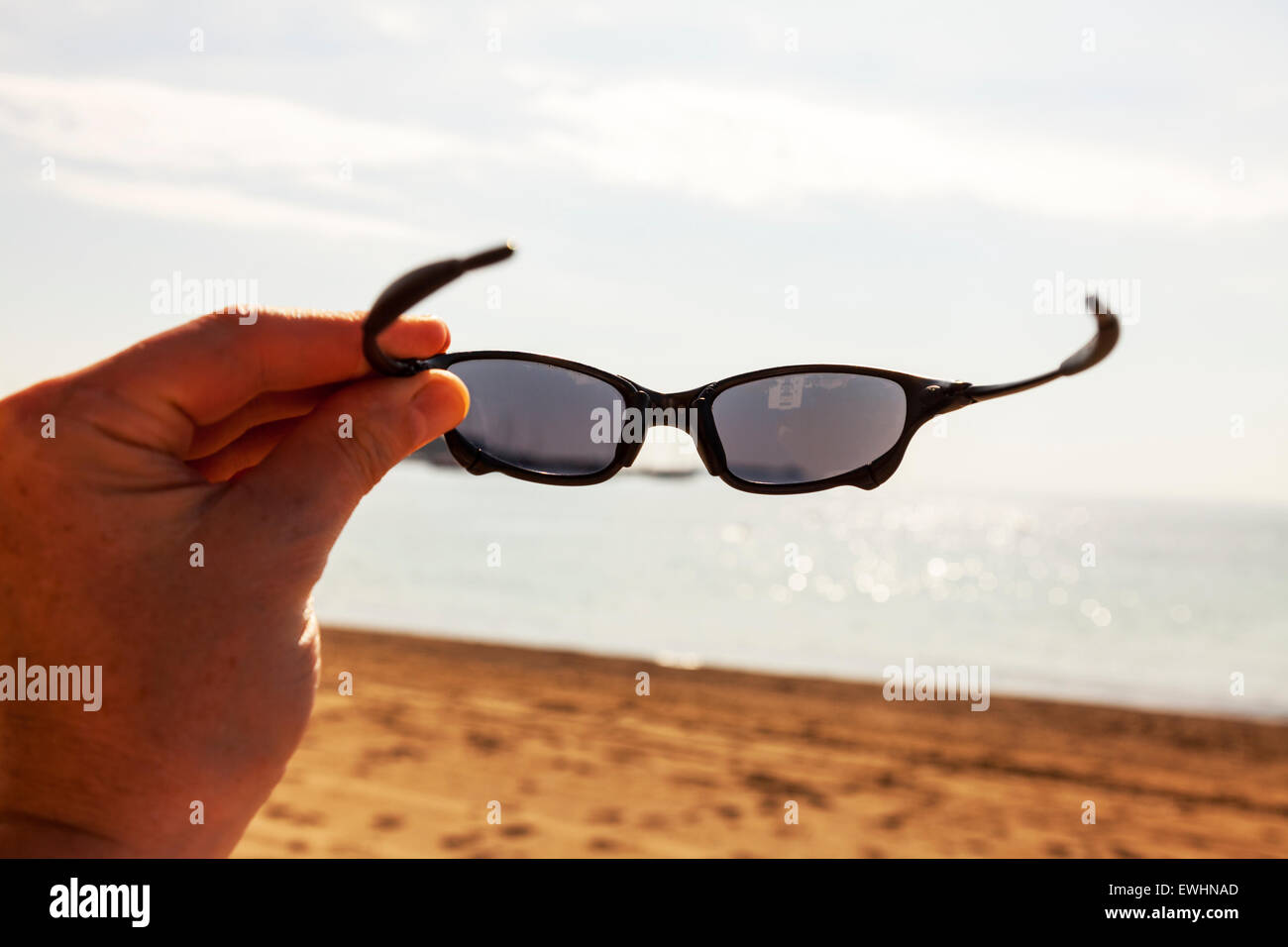 Gafas de sol poniendo en vacaciones de playa sol protección ocular Gafas de sol Oakley Santa Eulalia del Rio Ibiza España resort beach Fotografía de stock Alamy