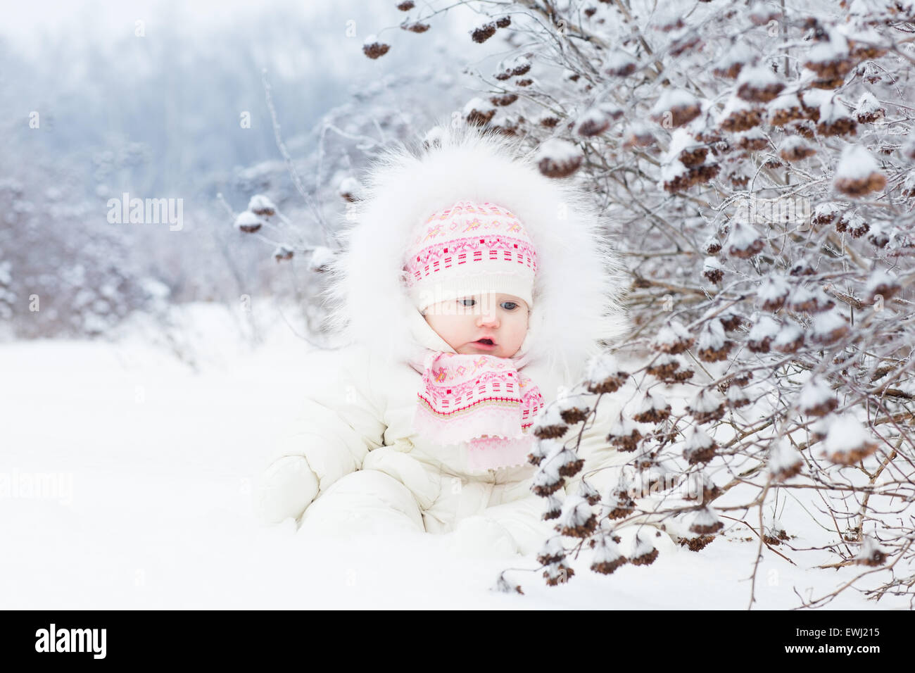 Hermoso bebé niña jugando en la nieve. Foto de stock