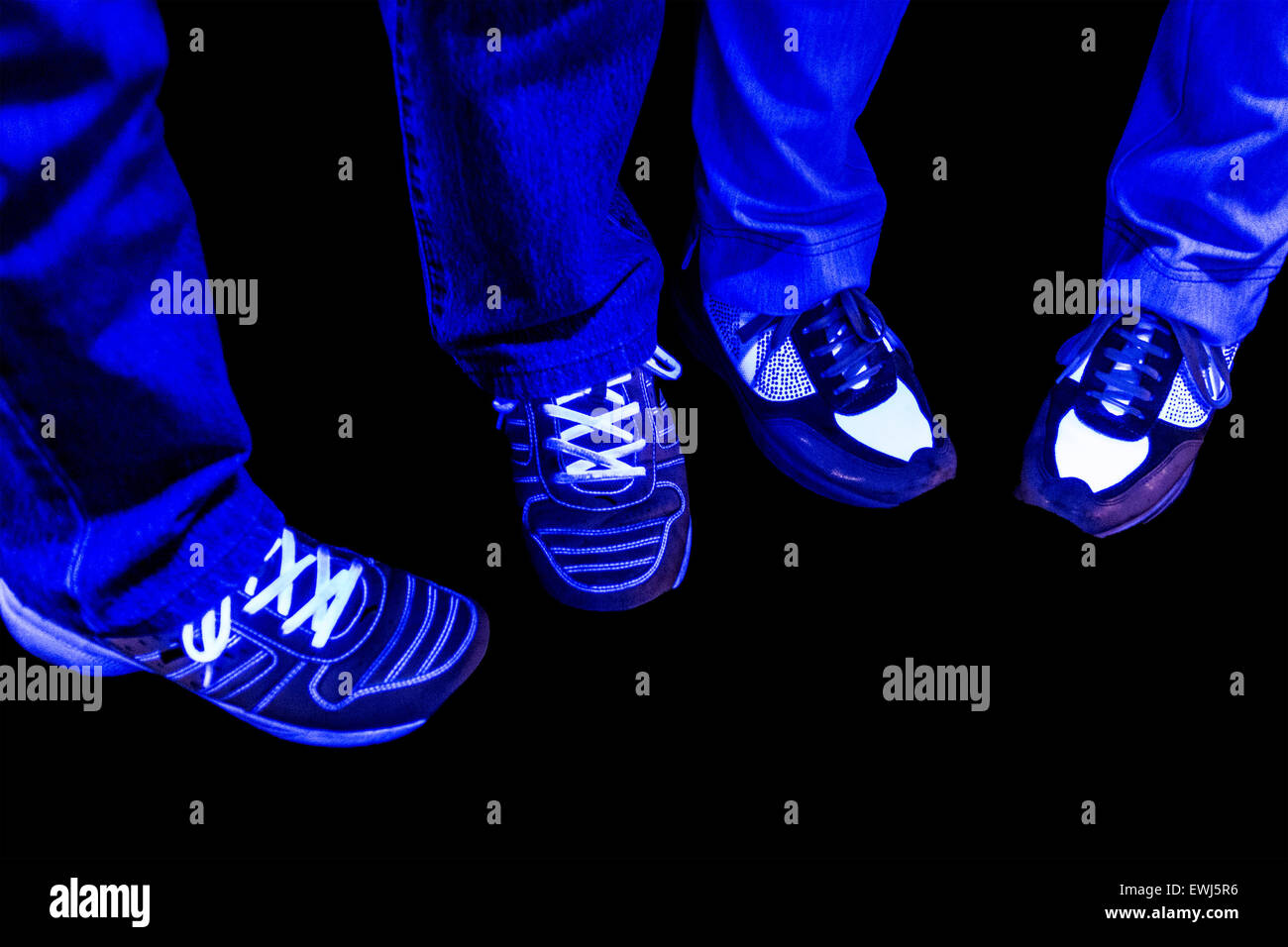 Los pantalones vaqueros y zapatillas con luz negra en discoteca Foto de stock