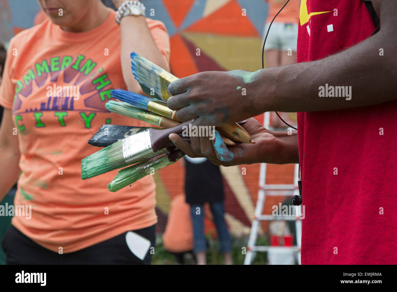 Detroit, Michigan - Adultos jóvenes limpiar los cepillos después de pintar una pared en el suroeste de Detroit. Foto de stock