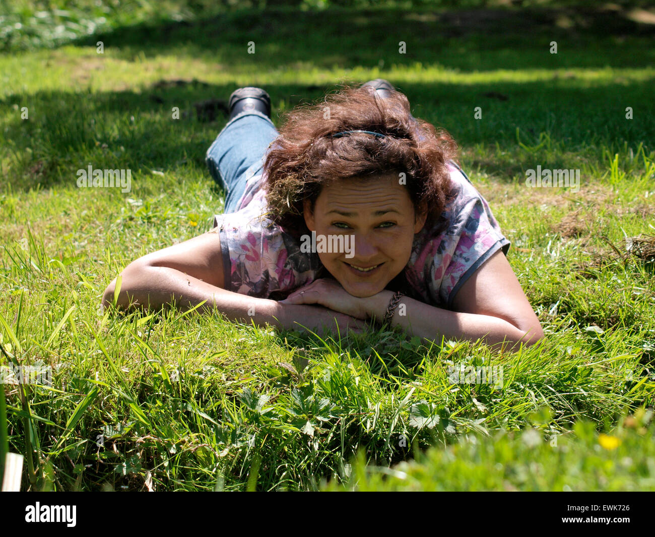Mujer de 40 años de edad tendido sobre la hierba mirando a la cámara, Somerset, Reino Unido Foto de stock
