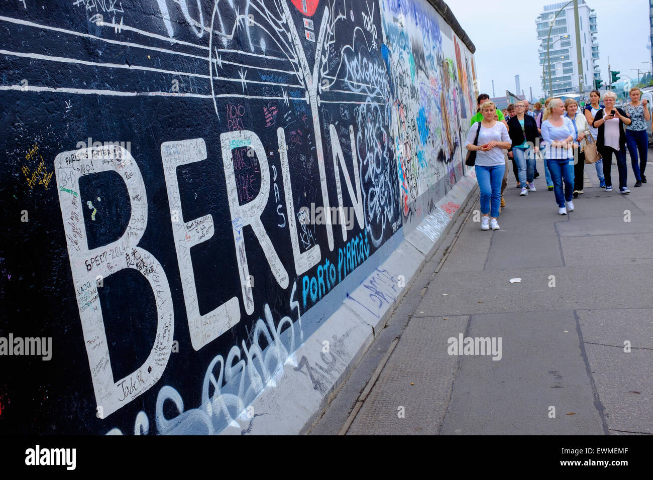 Los turistas atravesar el Muro de Berlín la sección restante en East Side Gallery con muchas pinturas murales y graffiti en Friedrichshain Foto de stock