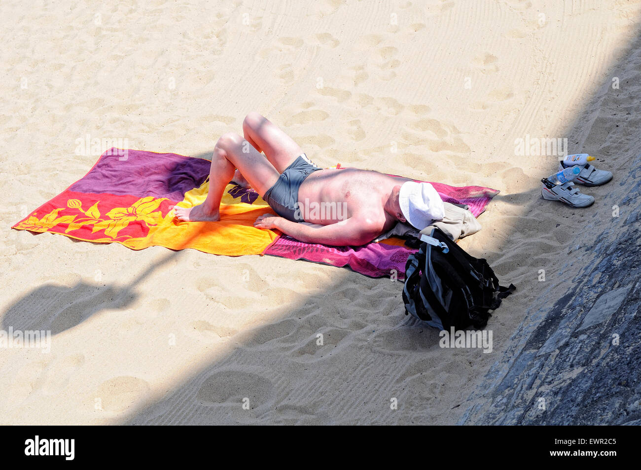 Hombre dormido bajo el sol, con la piel quemada en la playa de Saint-Jean-de-Luz (Donibane Lohizune) en un día de verano. Francia. Foto de stock