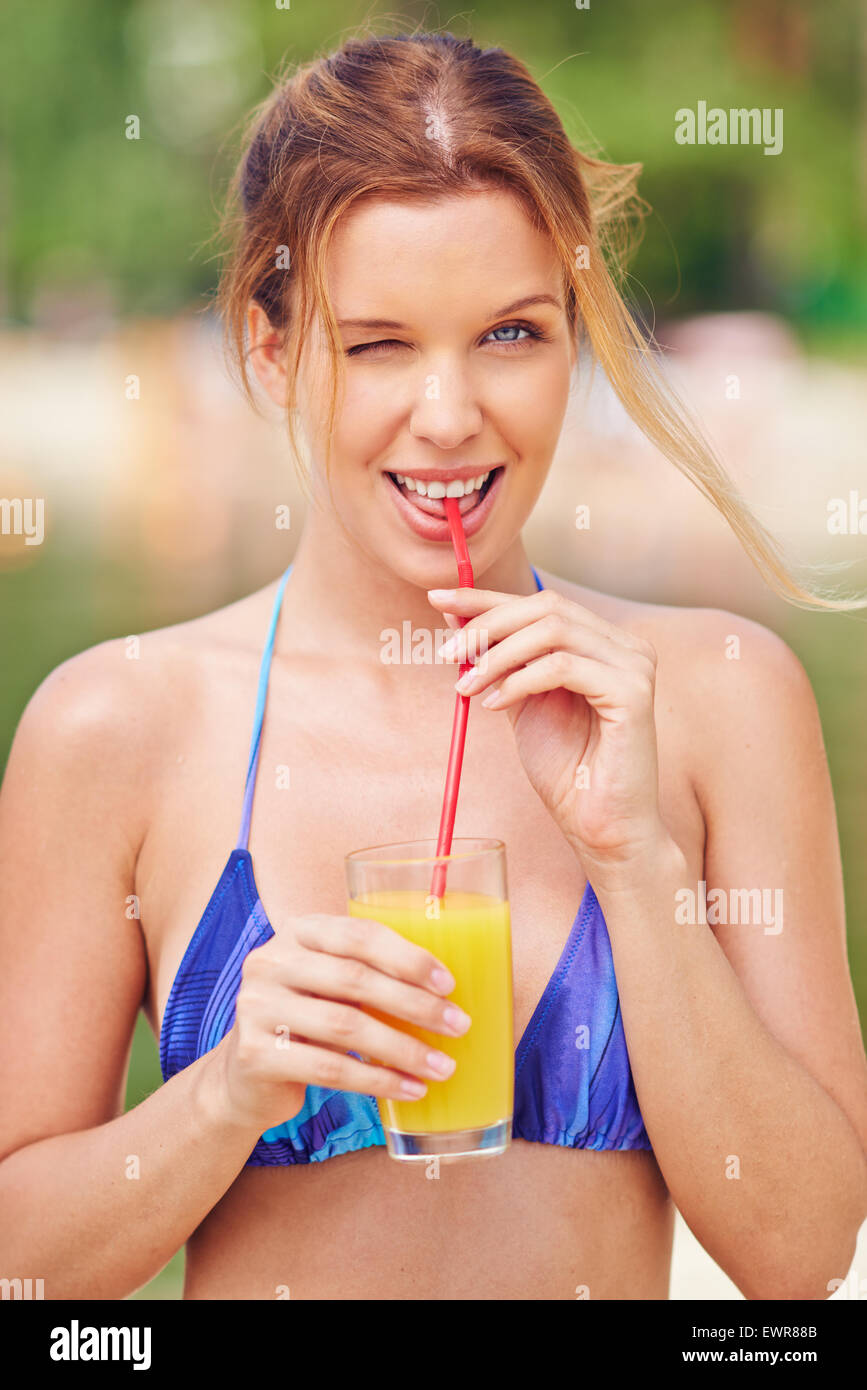 Feliz mujeres en bikini beber zumo de naranja y un guiño Fotografía de stock - Alamy Feliz mujeres en bikini beber zumo de naranja y un guiño Fotografía de stock - Alamy