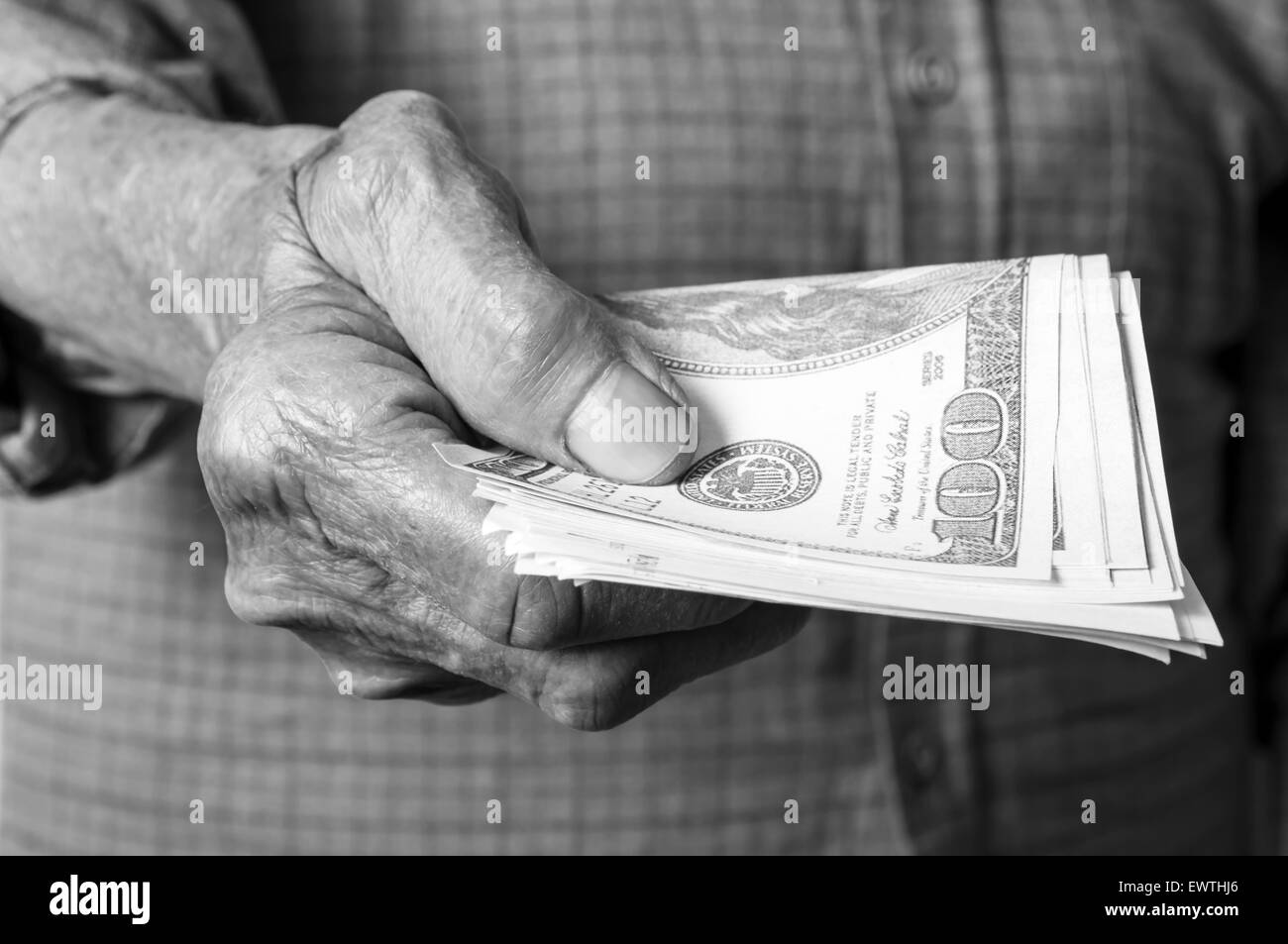 Dinero dolares en ancianos la mano. El enfoque selectivo. Foto de stock