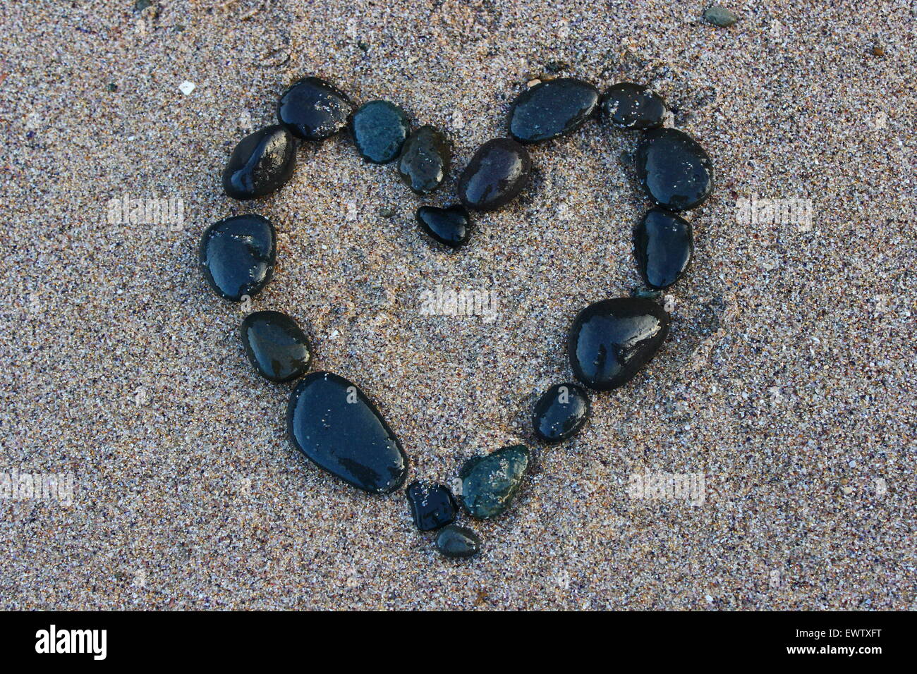 Corazón negro en la arena Foto de stock