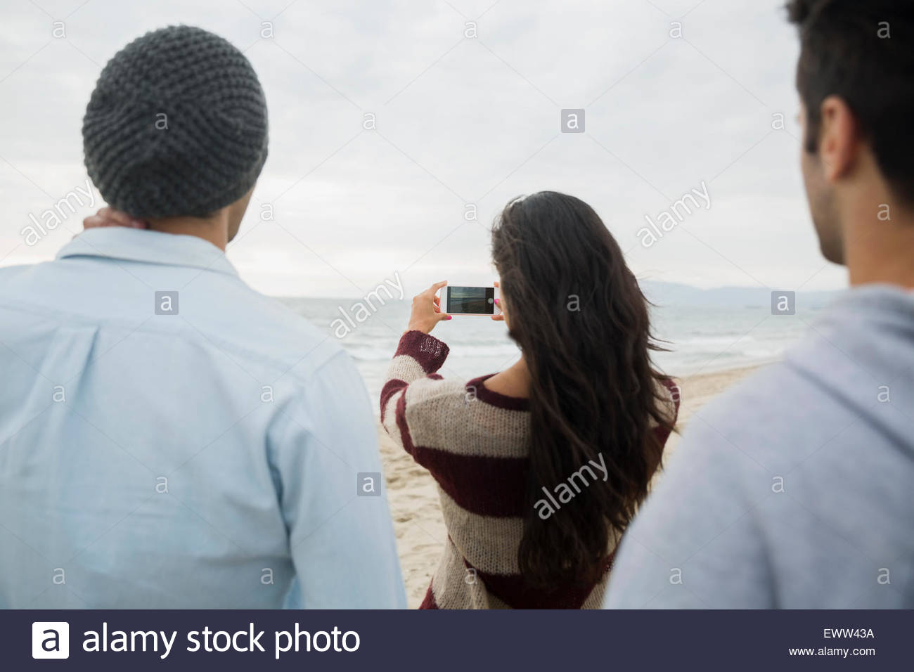 Amigos fotografiando ocean con teléfono con cámara en la playa Foto de stock